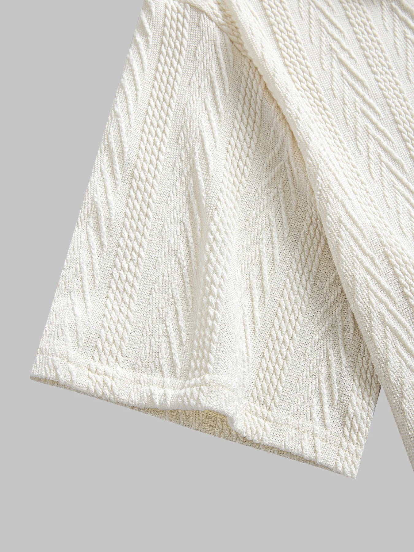 Beige knit polo shirt with structured collar and rolled short sleeves — light neutral tone with subtle pattern and stretch.